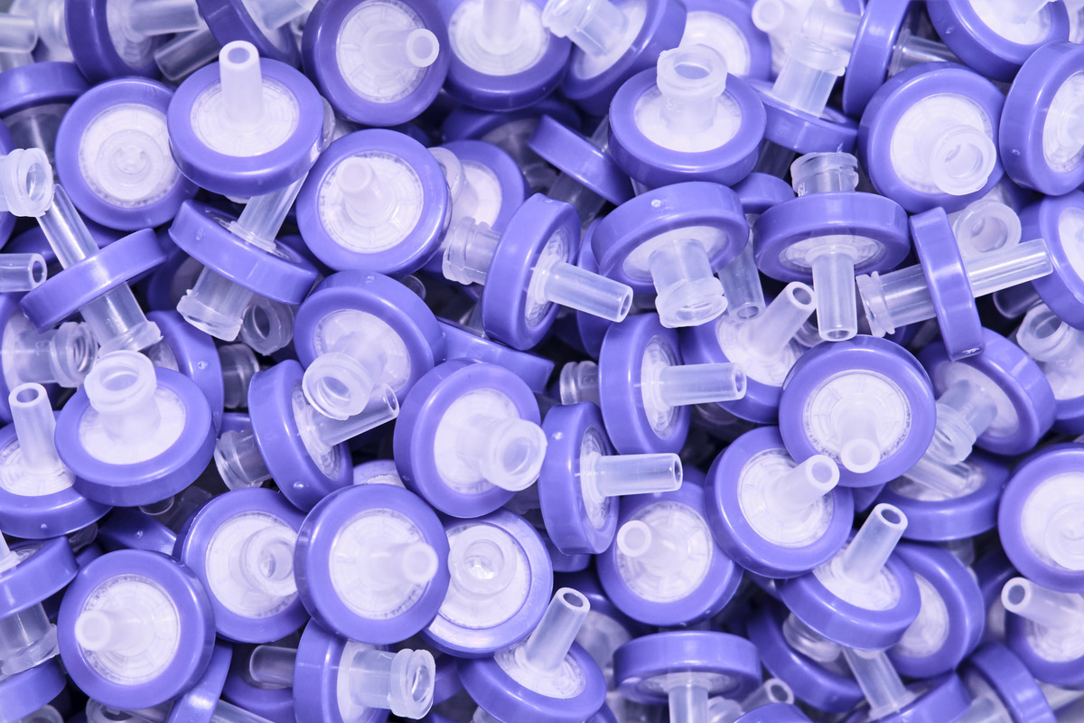 PTFE membrane syringe filters with purple bases and different pore sizes piled on top of each other.