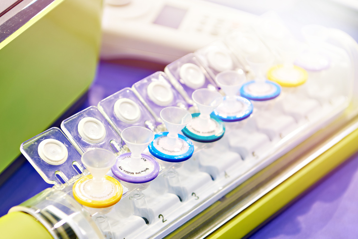 A long plastic tray placed on a table with multiple syringe filters of different colors positioned next to each other.