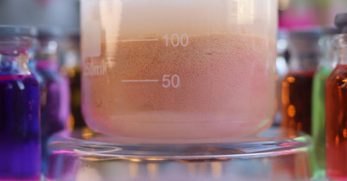 A close-up of the bottom of a large glass sampling beaker with a pink liquid inside. The liquid is separated.